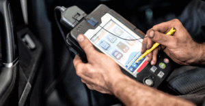 A close-up shot captures a man, with fair skin, holding a diagnostic tablet in both hands
