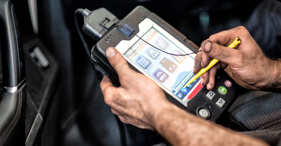 A close-up shot captures a man, with fair skin, holding a diagnostic tablet in both hands