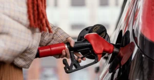 A close-up shot captures a person filling a car with petrol.