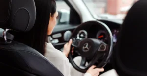 A medium shot captures a 30-year-old Asian woman with fair skin and long, straight black hair, driving a car