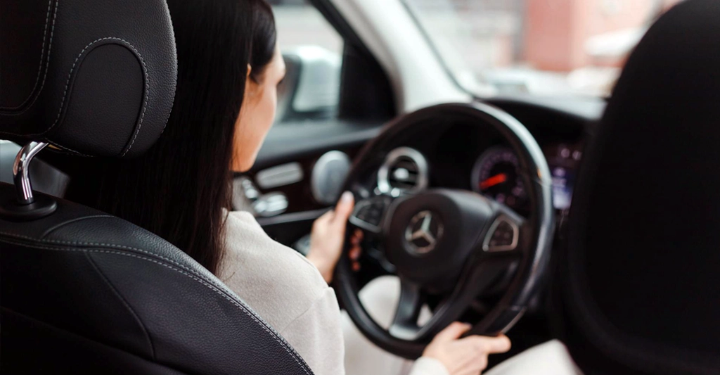 A medium shot captures a 30-year-old Asian woman with fair skin and long, straight black hair, driving a car