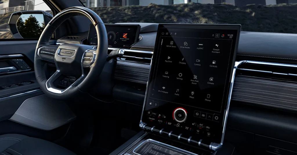  2025 GMC Sierra EV Denali car interior featuring a large, vertical touchscreen with various app icons on a sleek dashboard, conveying a high-tech, luxurious feel.
