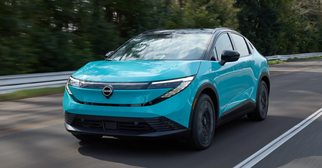 A sleek turquoise electric 2026-Nissan-LEAF drives along a tree-lined road, exuding modernity and eco-friendliness. The scene suggests a serene, sustainable journey.