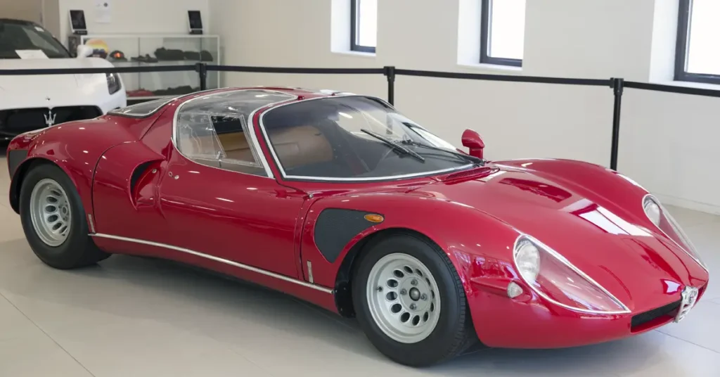 A red Alfa-Romeo-33 sports car parked in a modern showroom, showcasing its sleek design and polished exterior.