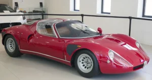 A red Alfa-Romeo-33 sports car parked in a modern showroom, showcasing its sleek design and polished exterior.
