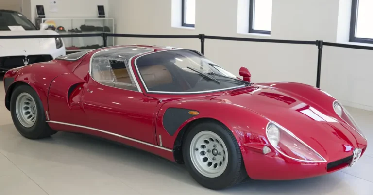 A red Alfa-Romeo-33 sports car parked in a modern showroom, showcasing its sleek design and polished exterior.
