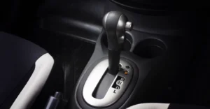 A close-up shot of a car's automatic gear shift, featuring a black and silver gear stick positioned in the center of the frame.
