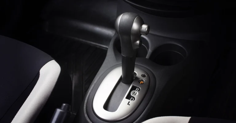 A close-up shot of a car's automatic gear shift, featuring a black and silver gear stick positioned in the center of the frame.