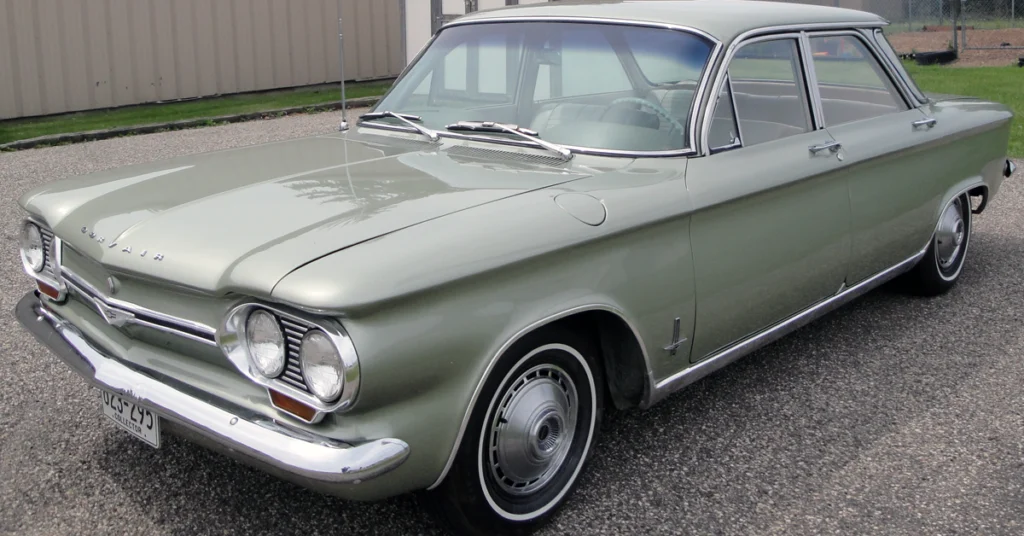 Vintage light green Chevrolet Corvair (1960) car with a sleek design, rounded headlights, and chrome accents, parked on a gravel surface, conveying a nostalgic, classic vibe.