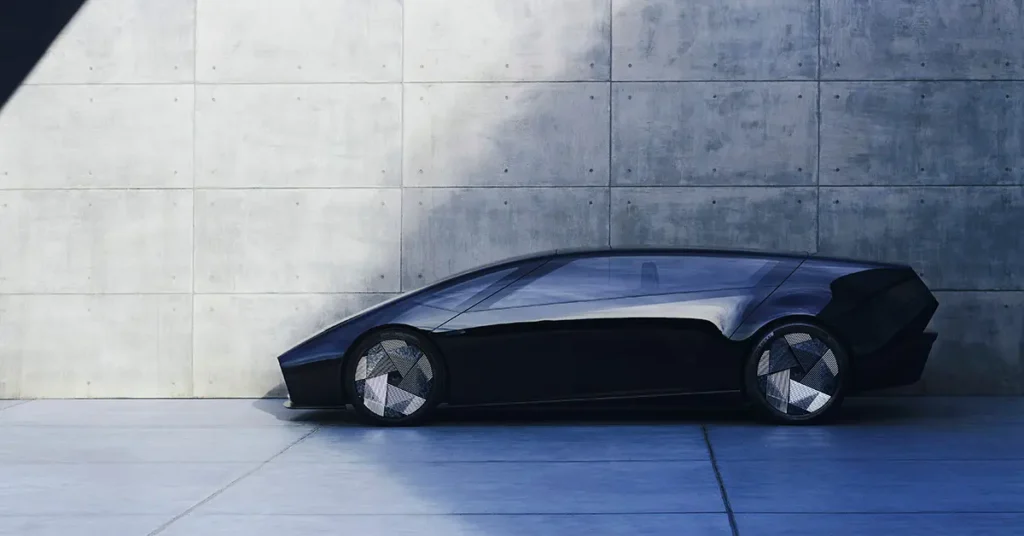 A sleek, futuristic black car Honda New car electric 0 Series with a minimalist design parked against a concrete wall