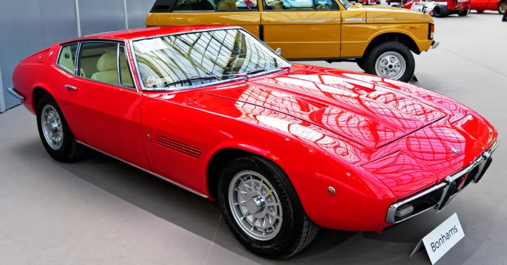 A vibrant red Maserati Ghibli Spyder (1969)sports car displayed in a stylish showroom, highlighting its design and features.