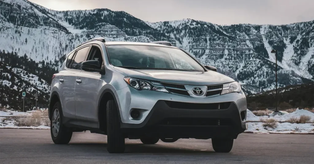 A 2019 Toyota RAV4 parked in a parking lot, surrounded by other vehicles and greenery in the background