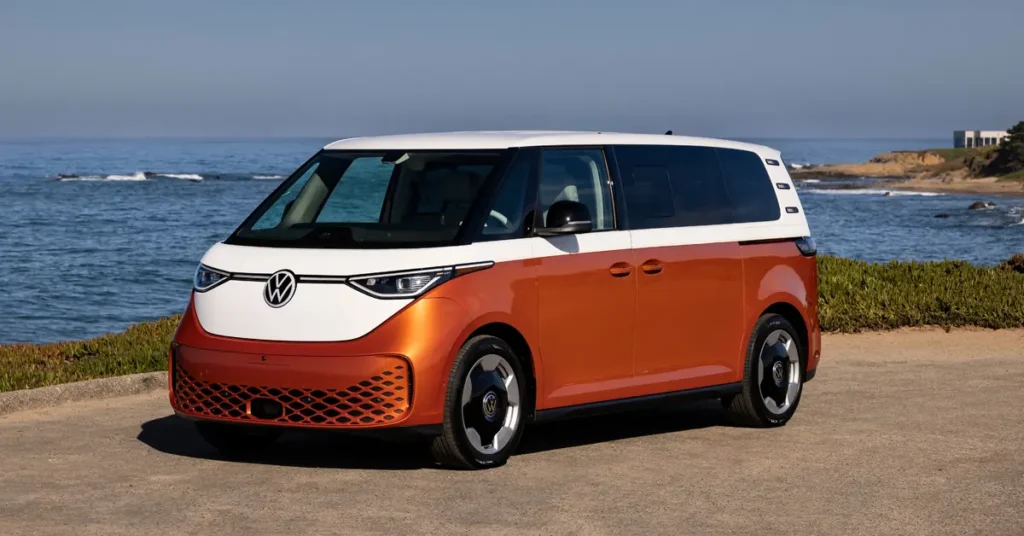 A Volkswagen ID.3 electric van parked on a sandy beach with waves gently lapping at the shore in the background
