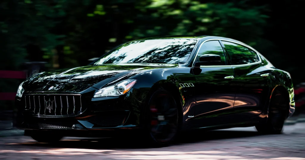 A sleek, black Maserati Ghibli sedan is captured in a dynamic, low-angle shot, emphasizing its luxurious design and powerful stance.
