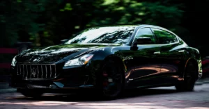 A sleek, black Maserati Ghibli sedan is captured in a dynamic, low-angle shot, emphasizing its luxurious design and powerful stance.