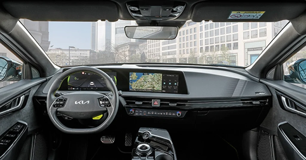 A medium shot of the interior of a Kia EV6 GT car, focusing on the dashboard and front seats. The dashboard is sleek and modern, featuring a large infotainment screen that displays a map.