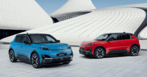 Two brand new Nissan Micra electric cars, one in bright blue and the other in vibrant red, are parked side by side on a light gray tiled surface.