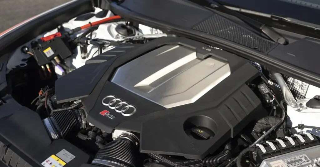 A detailed view of an Audi RS engine bay, showcasing the V6 engine with a prominent silver and black engine cover.