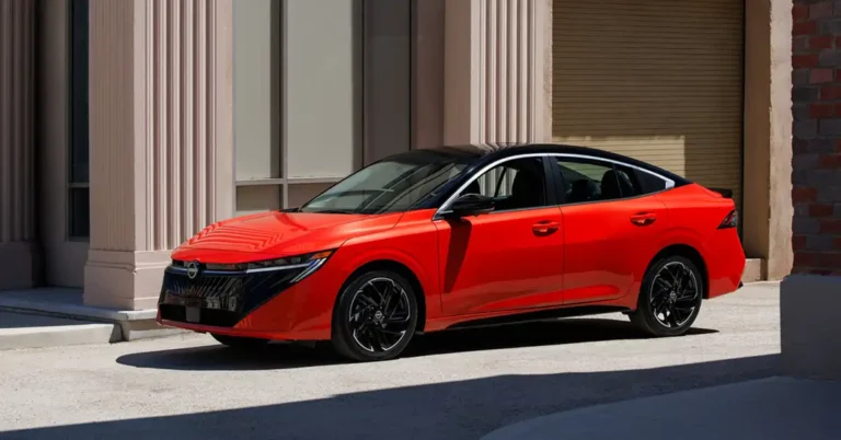A vibrant red 2026 Nissan Sentra sedan with a sleek black roof is parked on a concrete surface, bathed in natural light. The car's design features sharp, angular lines and modern LED headlights.