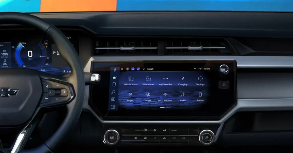 A detailed interior shot of a 2027 Chevrolet Bolt EUV, focusing on the dashboard and steering wheel. The dashboard is predominantly black with silver accents, featuring a large central touchscreen display showing various vehicle functions and settings.