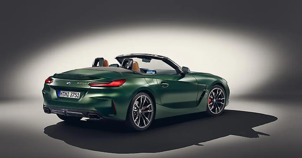 A studio shot of a green BMW Z4 M40i roadster, with its top down, is presented from a rear three-quarter perspective. The car's exterior is a deep, forest green, contrasting with the tan leather interior visible in the seats.