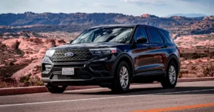 A black Ford Explorer SUV is parked on a paved road with a desert landscape in the background. The SUV is facing forward, showcasing its front grille, headlights, and bumper. The license plate is visible, reading "8LEC225". The vehicle appears clean and well-maintained.
