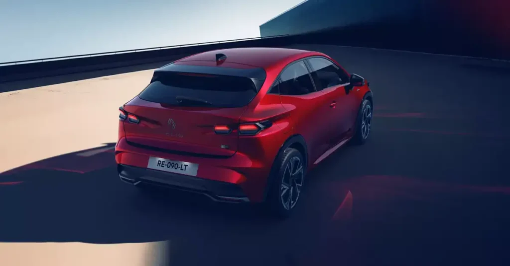 A red Renault Renault Clio 2025 car is captured from a rear three-quarter perspective, positioned on a light-colored surface that appears to be a ramp or elevated platform.