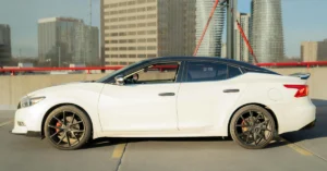 A side view captures a white Nissan Maxima with a black roof, parked on a concrete surface marked with yellow lines.