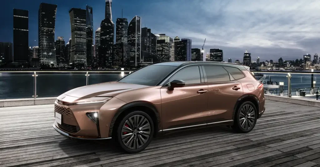 A bronze Toyota Crown Estate 2025 SUV is parked on a wooden platform with a cityscape in the background. The car has a sleek, modern design with a black roof and black accents around the windows and wheel wells.
