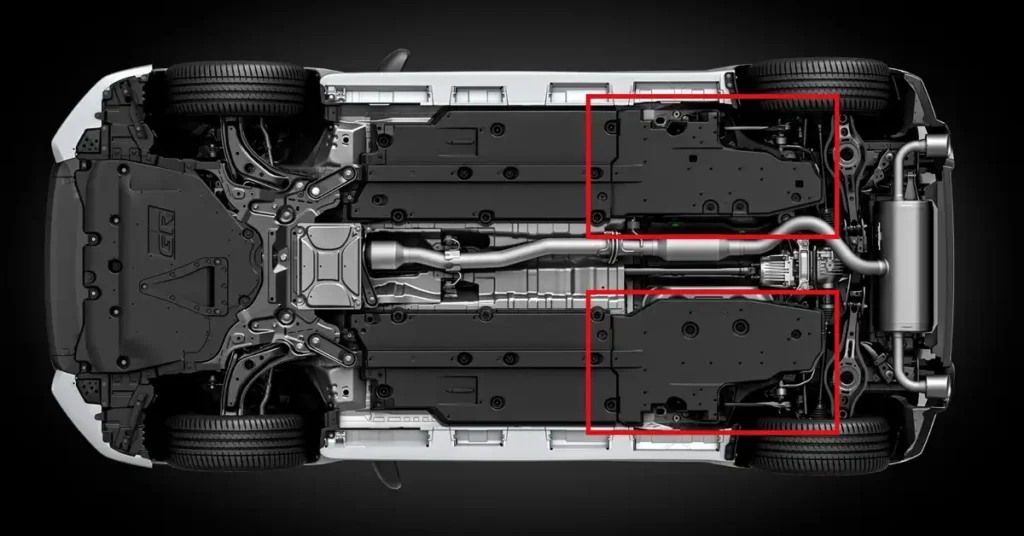 A digital rendering of the underside of a Toyota GR Yaris car, set against a stark black background. The car is positioned upside down, revealing its undercarriage in detail. The tires are prominently displayed at the four corners, exhibiting a standard tread pattern.