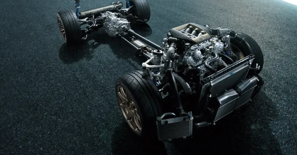 A detailed view of a 2025 Nissan GT-R car chassis, showcasing the engine, wheels, and suspension system, set against a dark, speckled background. The engine, a complex assembly of metal components, is prominently displayed, with its various parts intricately connected.