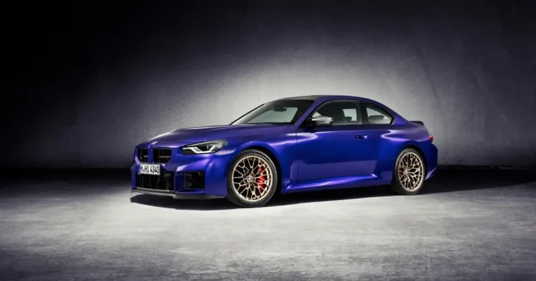 A sleek, metallic blue 2026 BMW M2 CS  coupe is showcased in a studio setting. The car is positioned at an angle, with its front left side facing the viewer.