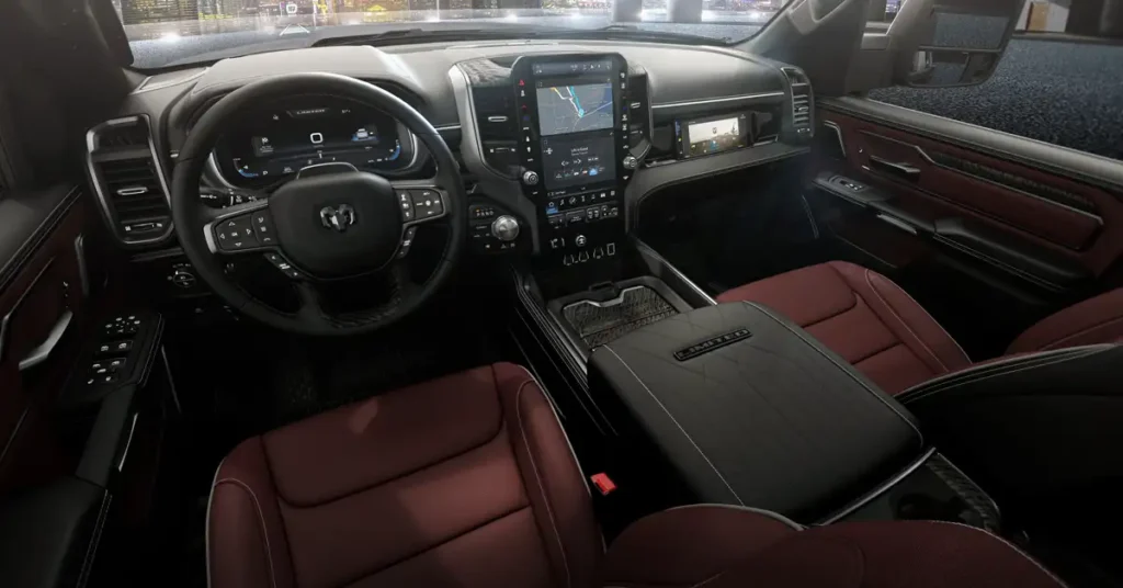 A photograph showcases the interior of a The 2026 Ram 1500 REV , specifically the dashboard and front seats, under soft, diffused lighting. The dashboard is predominantly black with silver accents, featuring a large touchscreen display in the center, which shows a navigation map