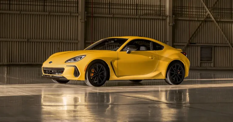 A bright yellow 2026 Subaru BRZ is parked in a large, industrial-looking garage. The car is positioned at a slight angle, facing left, with its front end closer to the viewer.
