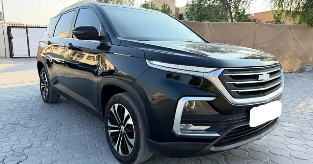 A black Chevrolet Captiva SUV is parked on a paved driveway. The car is facing the viewer at a slight angle, with its front right side most prominent. The SUV has a sleek, modern design with chrome accents around the grille and headlights. The grille features horizontal slats and the Chevrolet logo in the center. The headlights are slim and angular, with integrated LED daytime running lights.