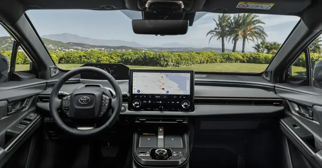 The image shows the interior of a 2025 Toyota bZ4X SUV, viewed from the driver's perspective. The dashboard features a large central touchscreen displaying a navigation map, a digital instrument cluster to the left, and a sleek steering wheel with integrated controls.