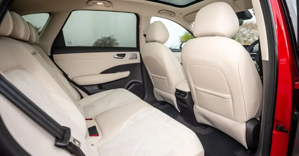 The image shows the interior of a MG MGS6 EV SUV, focusing on the rear seats. The seats are upholstered in a light cream-colored leather with a diamond-stitched pattern on the seat cushions.