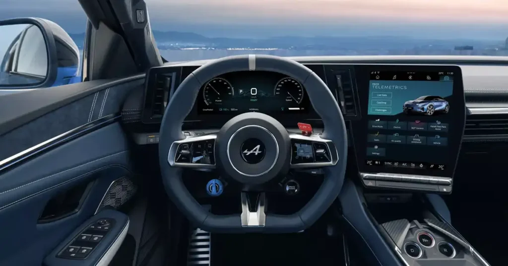 A close-up, eye-level shot showcases the interior of a 2026 Alpine A390, focusing on the steering wheel and dashboard. The steering wheel, in a dark blue, features a silver stripe at the top and the "Alpine" logo in the center. To the right of the steering wheel is a large, vertical touchscreen displaying "TELEMETRICS" and a blue sports car.