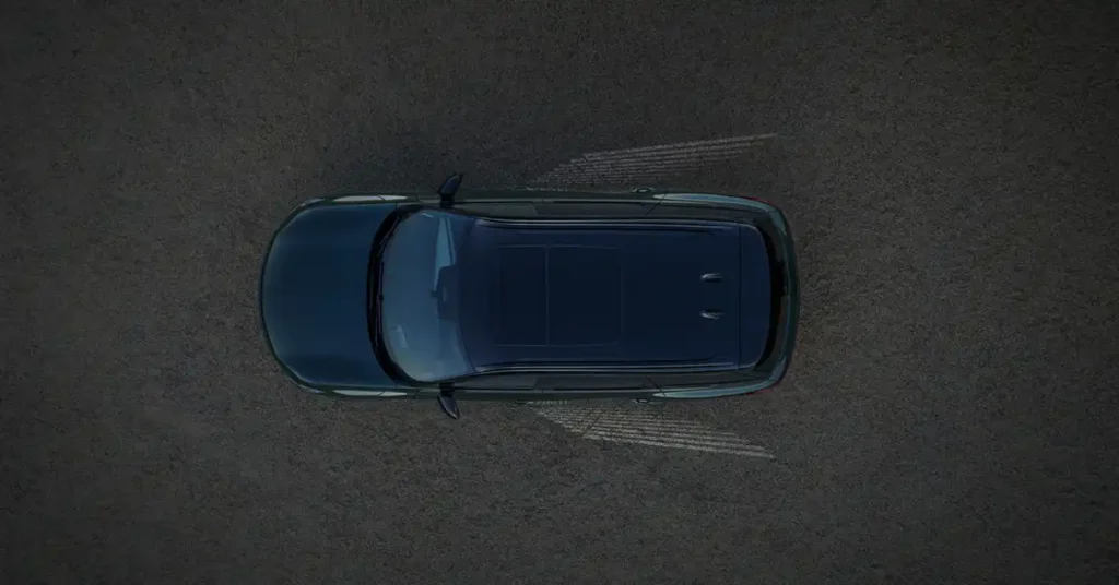 An overhead shot shows a dark blue 2026 INFINITI QX60 parked on a dark, textured surface. The car is positioned horizontally in the frame, with its front facing left.