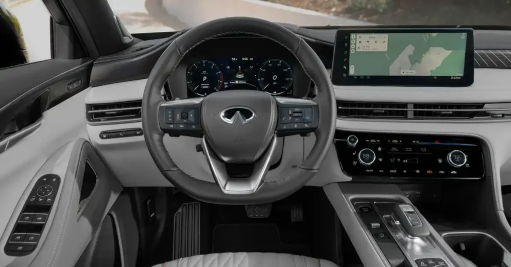 A close-up, eye-level shot showcases the interior of a 2026 INFINITI QX60, focusing on the dashboard and steering wheel.