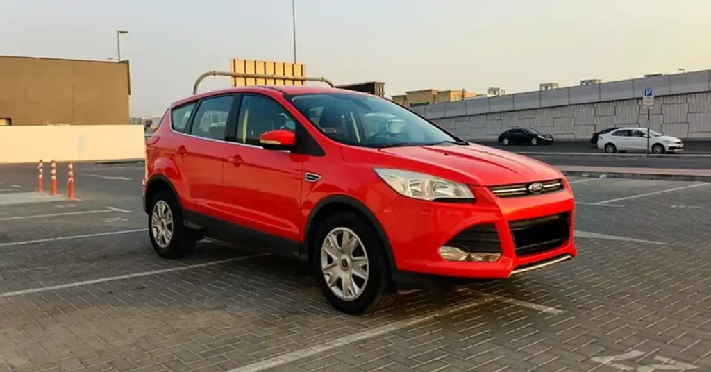 bright red Ford Escape UV is parked in an outdoor paved lot. The car is angled towards the viewer, with its front left side most prominent.