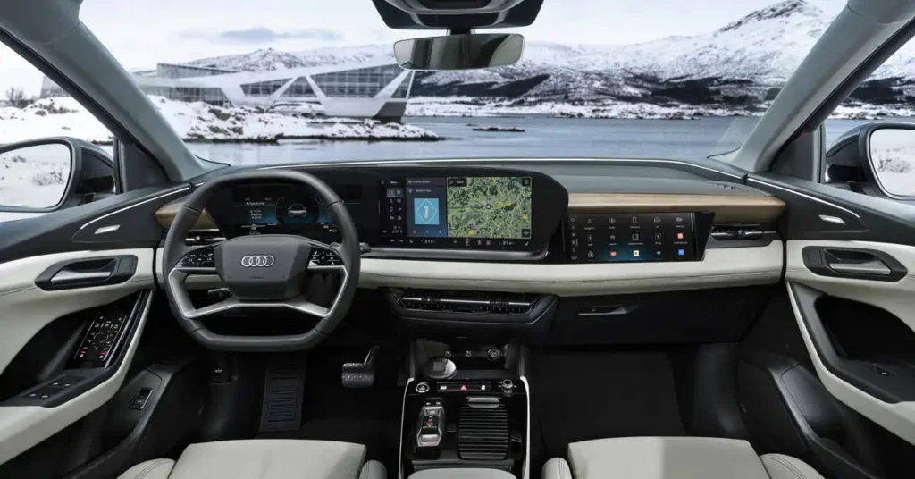 A wide-angle interior shot of a Audi e-tron dashboard shows a panoramic view of a snowy landscape through the windshield. The dashboard features a large, curved display screen with navigation and various icons, a digital instrument cluster behind the steering wheel, and a sleek, minimalist design with wood and leather accents.