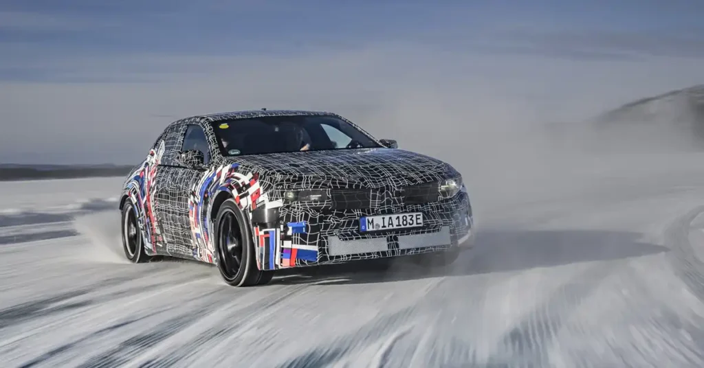 A camouflaged A BMW M 3 car is captured in a dynamic shot, drifting on a snow-covered track. The car, with its distinctive black and white grid pattern and colorful accents, is the central focus, kicking up a cloud of snow as it maneuvers.